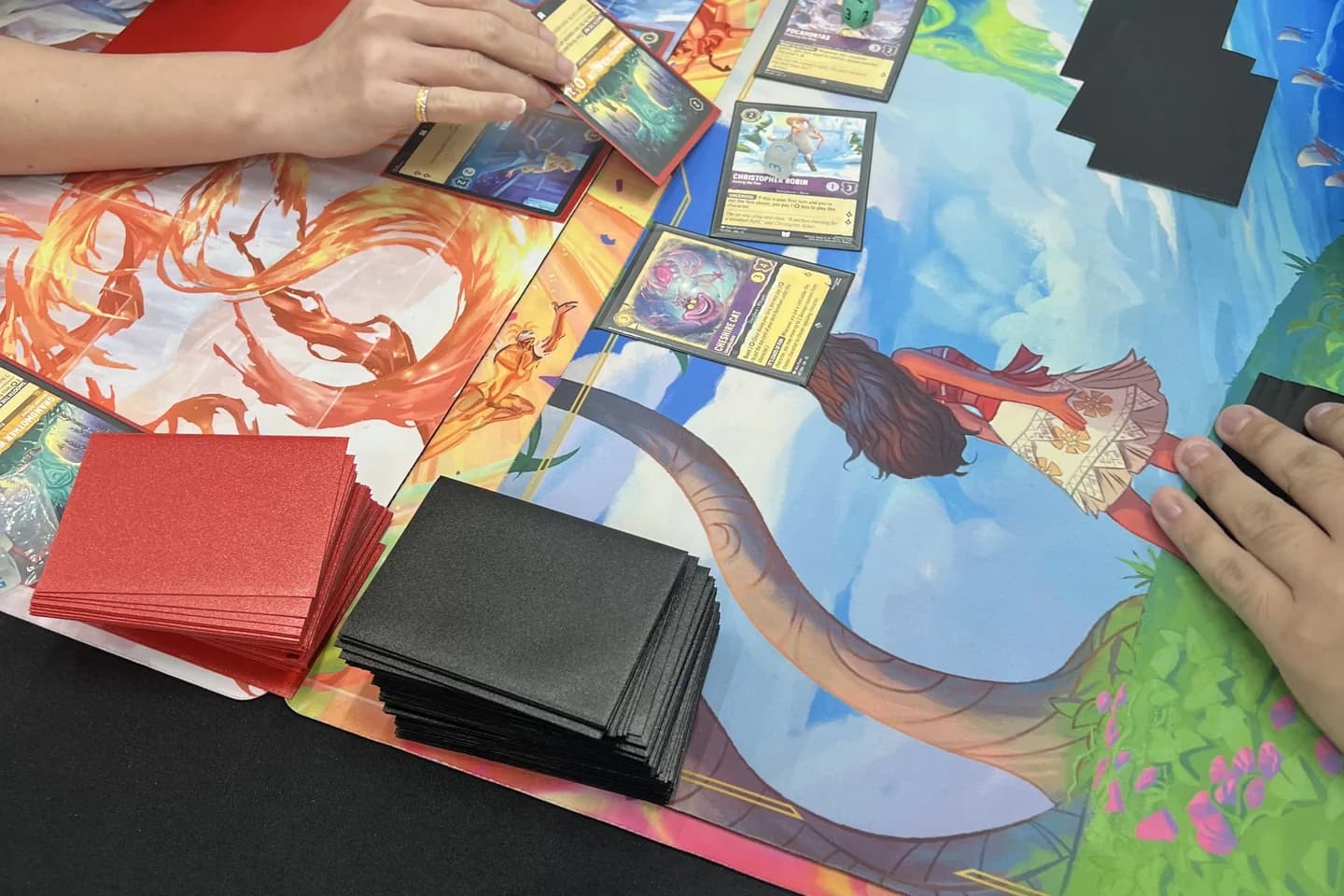 Three cards laid out on a colorful playmat during a game.