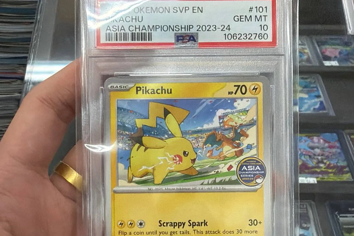 Close-up of a PSA-graded Pikachu card held over the display case.